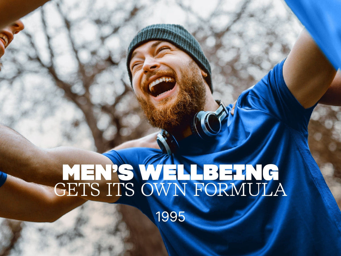Man in blue shirt and beanie with text 'Men's Wellbeing Gets Its Own Formula 1995' against a blurred natural background