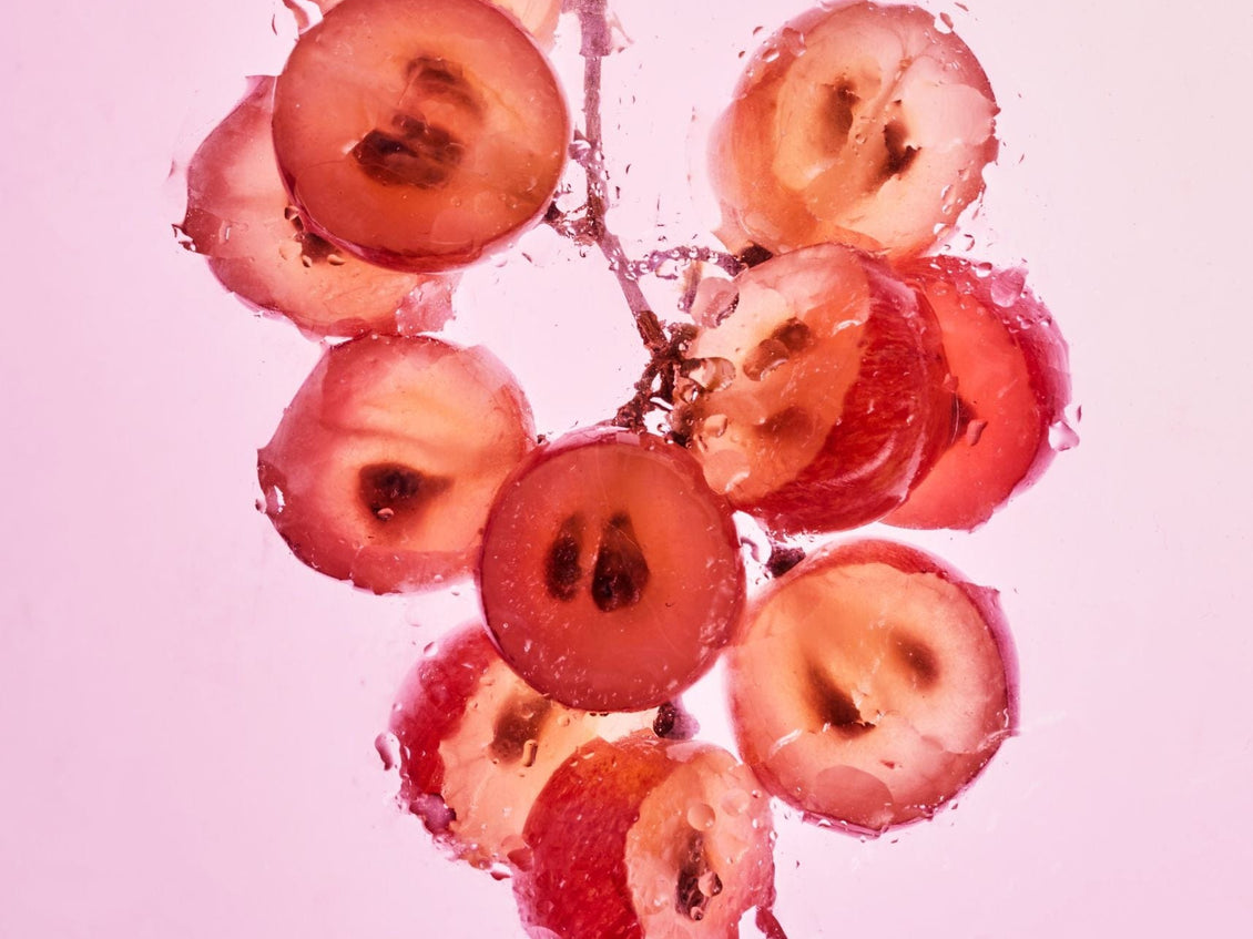 Sliced red grapes submerged in water, representing grape seed.