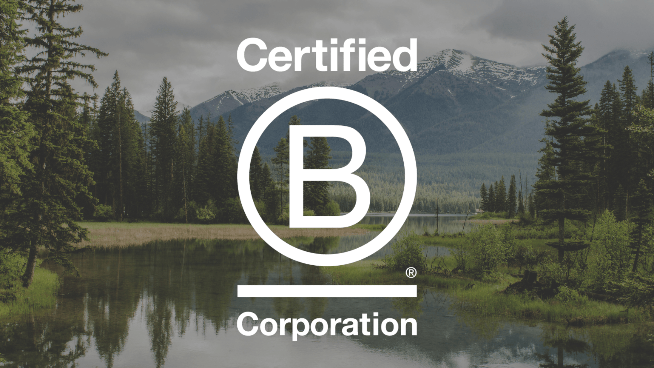 Certified B Corporation logo overlaid on a scenic background of a forested lake with mountains in the distance.