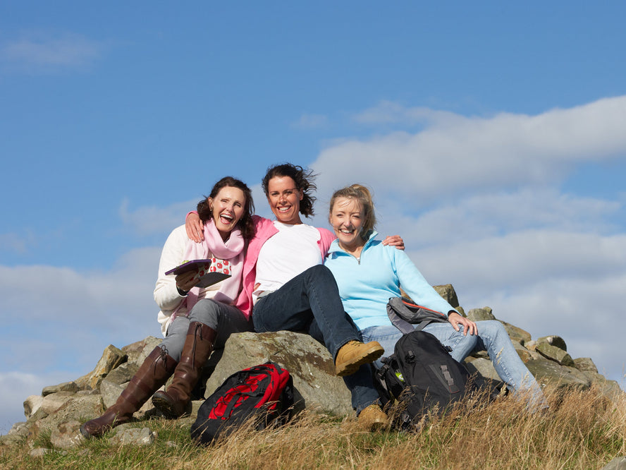 Group of happy smiling women sitting outside on mountain top