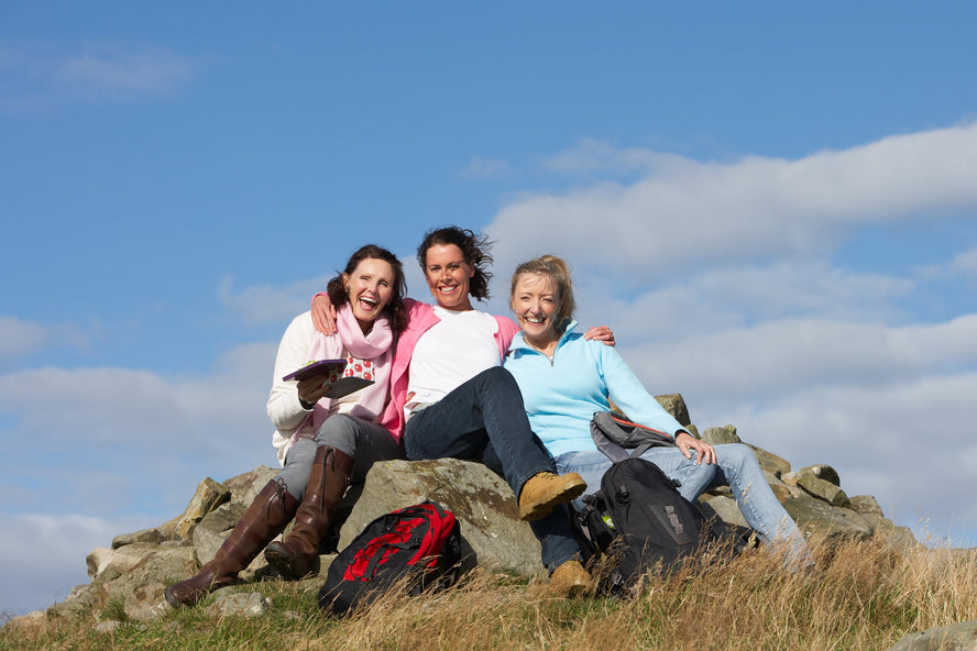 Group of happy smiling women sitting outside on mountain top