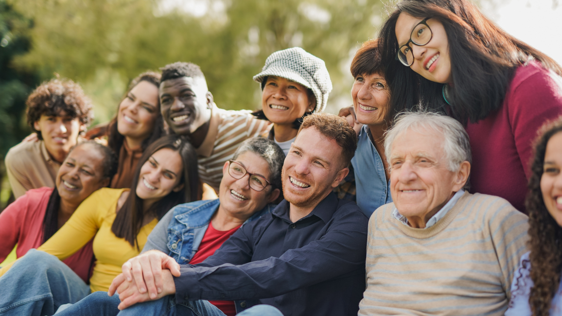 Group of people smiling and taking a photo outdoors.