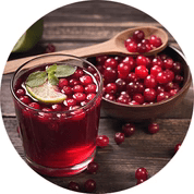 Glass of cranberry drink with fresh cranberries and a lime slice on a wooden surface