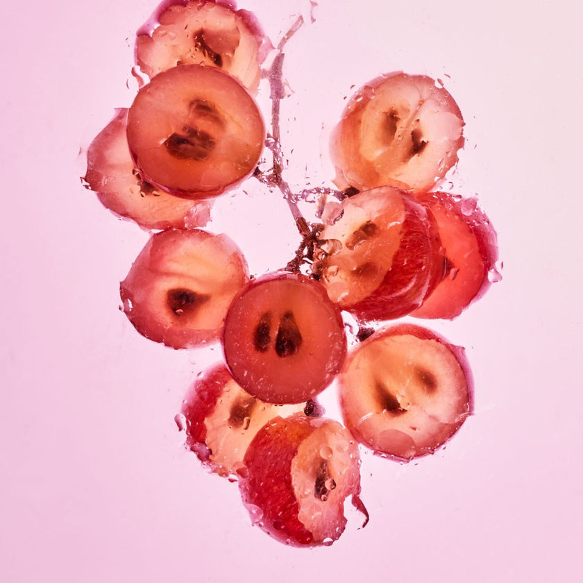 Sliced red grapes submerged in water, representing grape seed.