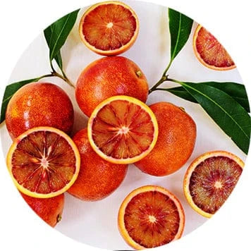 Whole and sliced blood oranges with green leaves on a light background